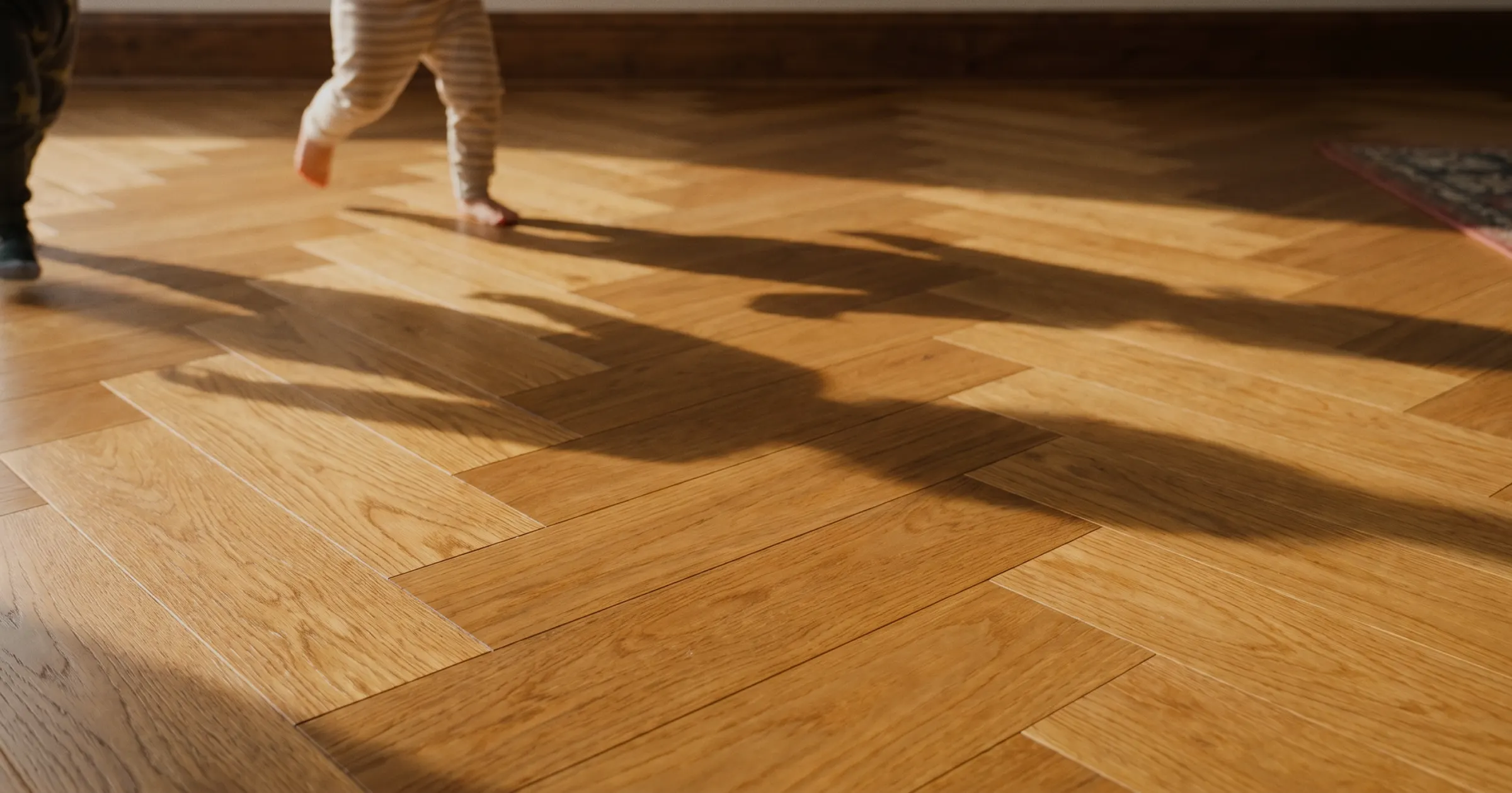 Sunlit herringbone hardwood hallway installed by Grain Design Flooring